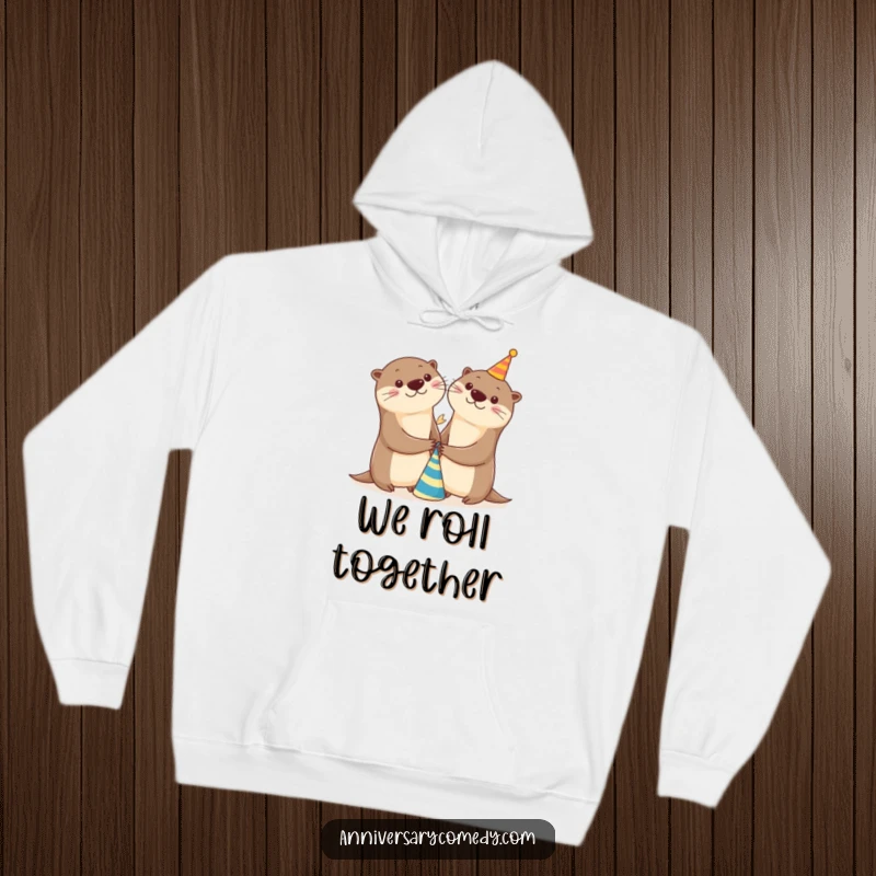 Funny otter hoodie with two happy otters holding hands by a small party hat, ideal for cozy and cheerful gatherings.
